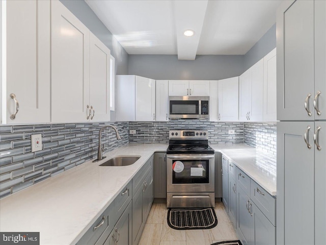 kitchen with backsplash, white cabinetry, sink, and stainless steel appliances