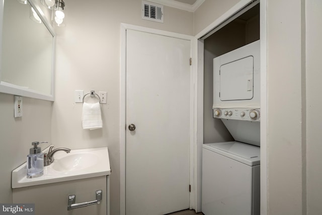 clothes washing area with stacked washer / dryer, crown molding, and sink