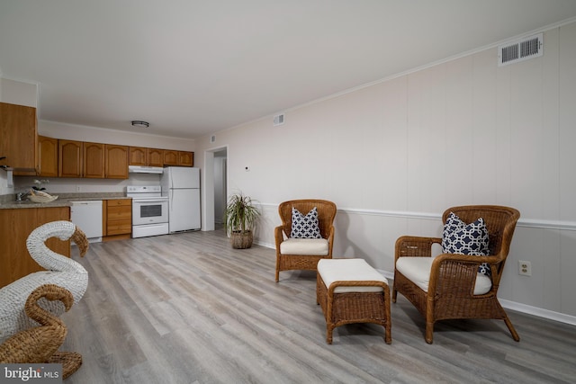 sitting room featuring crown molding and light hardwood / wood-style flooring