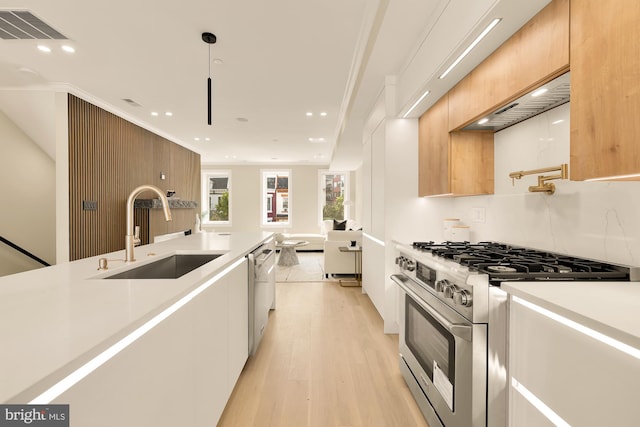 kitchen featuring sink, hanging light fixtures, stainless steel appliances, light hardwood / wood-style flooring, and white cabinets