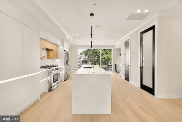 kitchen featuring appliances with stainless steel finishes, sink, a center island with sink, white cabinetry, and hanging light fixtures