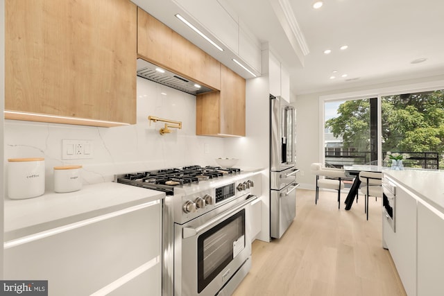 kitchen with high quality appliances, light brown cabinets, white cabinets, and ornamental molding