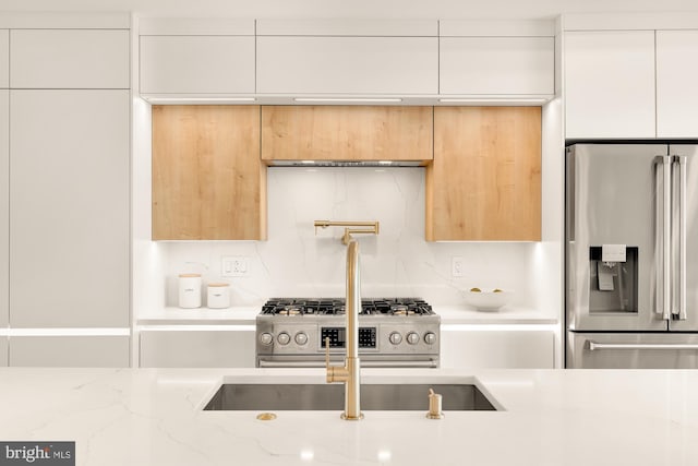 kitchen featuring light stone countertops, appliances with stainless steel finishes, backsplash, and white cabinetry