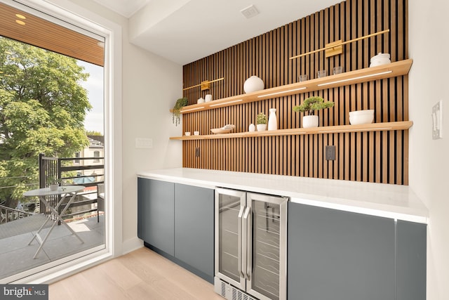 bar featuring gray cabinets, plenty of natural light, light hardwood / wood-style floors, and beverage cooler