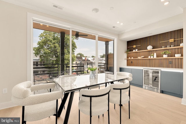 dining space with hardwood / wood-style floors, crown molding, and beverage cooler