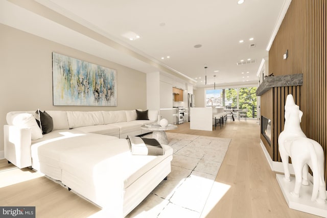 living room featuring light wood-type flooring and ornamental molding