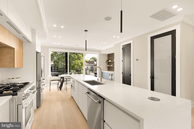 kitchen featuring appliances with stainless steel finishes, a kitchen island with sink, sink, pendant lighting, and white cabinetry