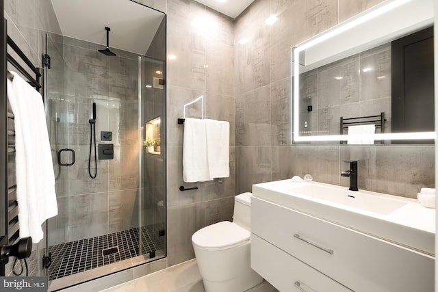 bathroom with vanity, a shower with shower door, tile walls, and toilet