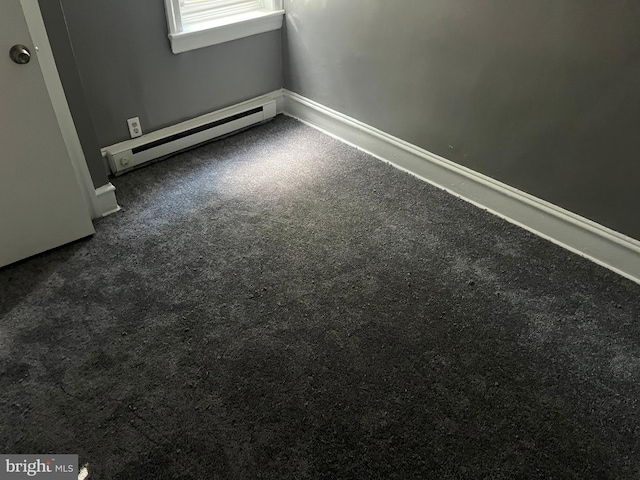 unfurnished room featuring dark carpet and baseboard heating