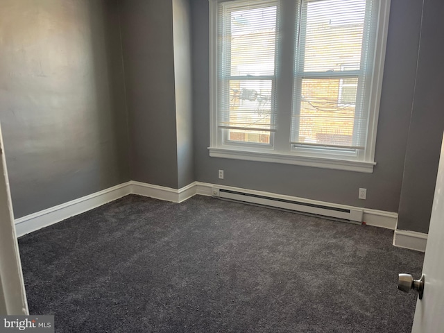 unfurnished room featuring dark carpet, plenty of natural light, and a baseboard heating unit