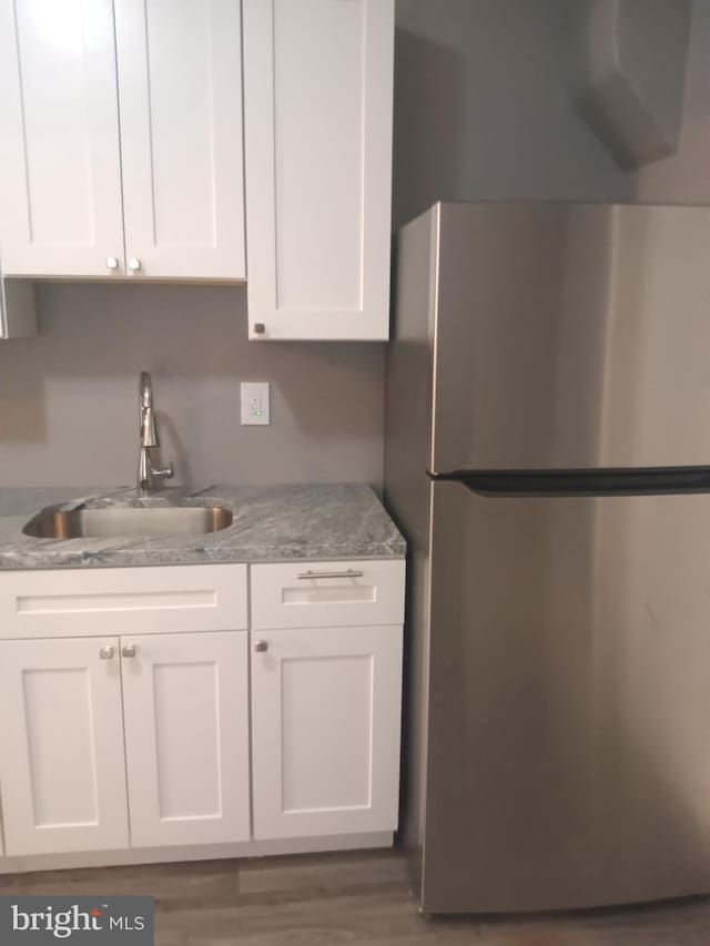 1635 S Etting St, Philadelphia, PA 19145 - kitchen featuring freestanding refrigerator, a sink, white cabinets, and wood finished floors