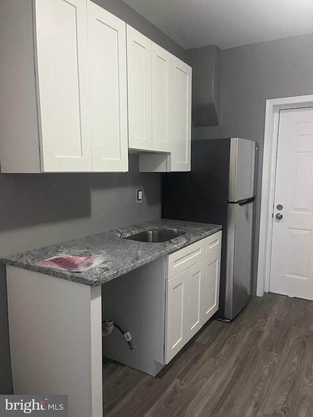 kitchen featuring stone countertops, dark hardwood / wood-style flooring, white cabinetry, and sink