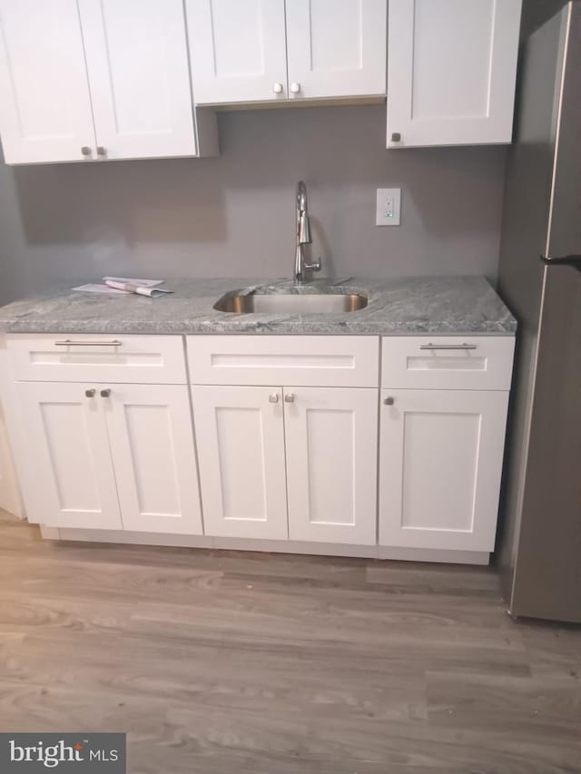 1635 S Etting St, Philadelphia, PA 19145 - kitchen featuring a sink, white cabinetry, freestanding refrigerator, light stone countertops, and light wood-style flooring
