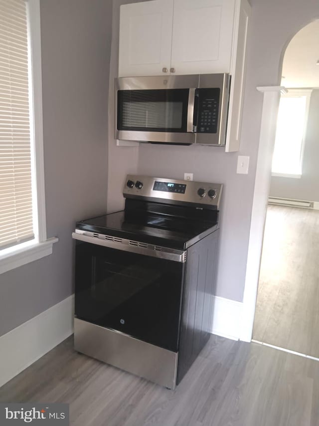 1635 S Etting St, Philadelphia, PA 19145 - kitchen with appliances with stainless steel finishes, arched walkways, white cabinets, and wood finished floors