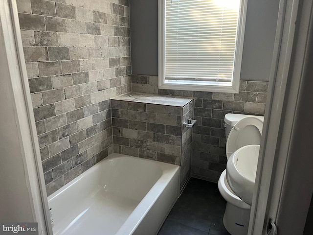 bathroom with tile patterned floors, a bathtub, tile walls, and toilet