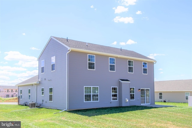 back of property featuring central AC unit and a yard