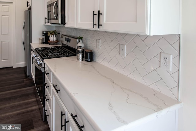 kitchen with dark wood-type flooring, appliances with stainless steel finishes, tasteful backsplash, light stone counters, and white cabinetry