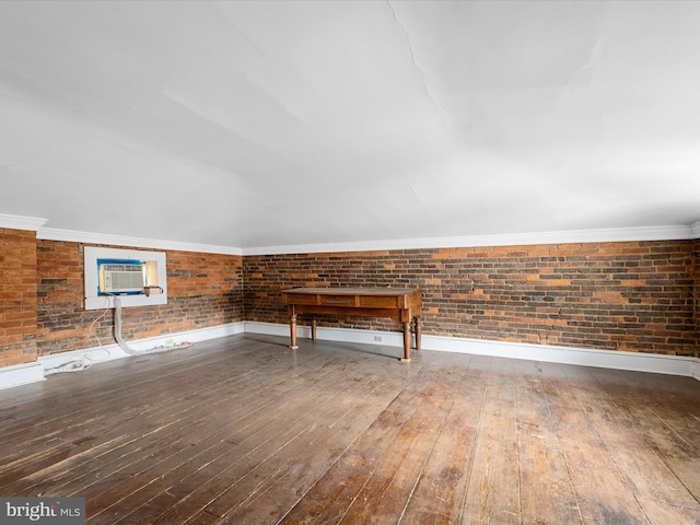 miscellaneous room featuring wood-type flooring, crown molding, and brick wall