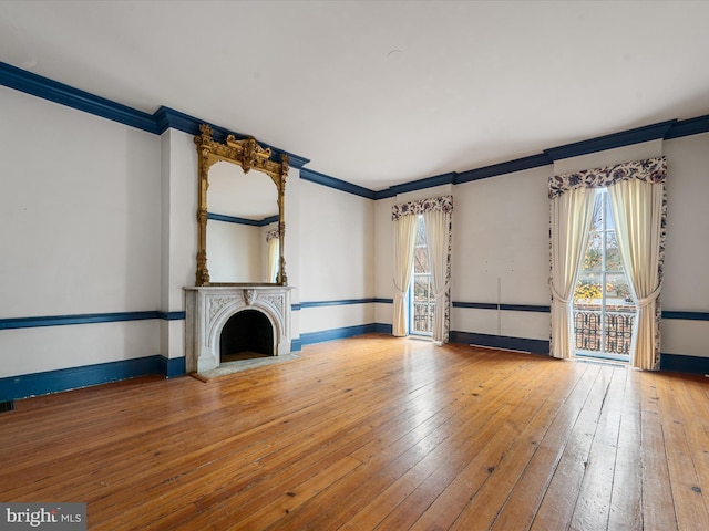 unfurnished living room with wood-type flooring and ornamental molding