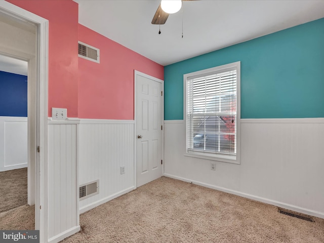 spare room with ceiling fan and light carpet