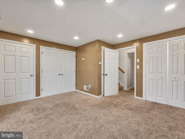 unfurnished bedroom with carpet flooring and multiple closets