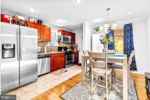 kitchen with a notable chandelier, pendant lighting, light hardwood / wood-style floors, appliances with stainless steel finishes, and ornamental molding