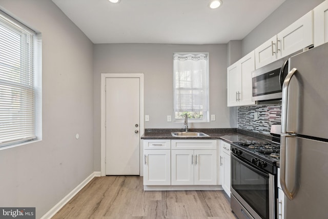 kitchen with sink, decorative backsplash, appliances with stainless steel finishes, light hardwood / wood-style floors, and white cabinetry