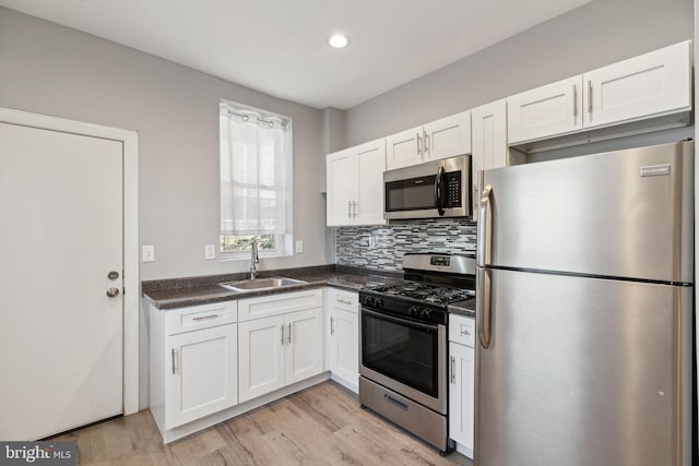 kitchen with white cabinets, sink, stainless steel appliances, and light hardwood / wood-style flooring