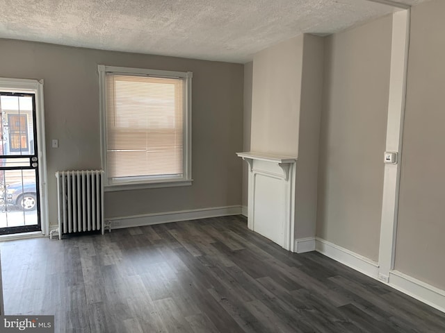 unfurnished living room with dark hardwood / wood-style floors, radiator heating unit, and a textured ceiling