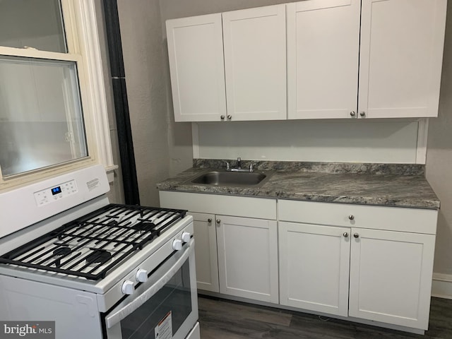 kitchen featuring white cabinetry, white gas range, dark wood-type flooring, and sink