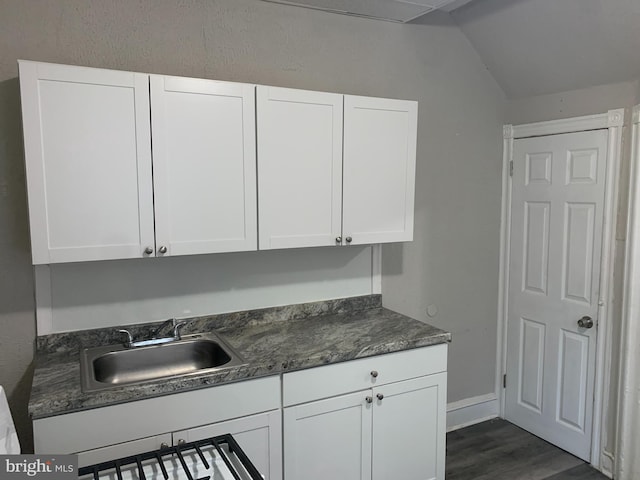 kitchen featuring sink, white cabinets, dark wood-type flooring, and lofted ceiling