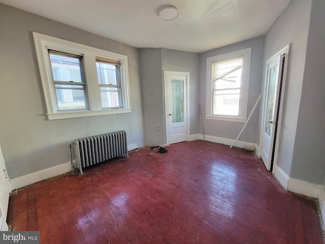 empty room with radiator heating unit and dark wood-type flooring