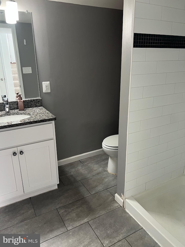 bathroom featuring tiled shower, vanity, and toilet