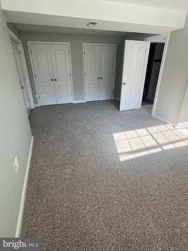 unfurnished bedroom featuring carpet floors and two closets