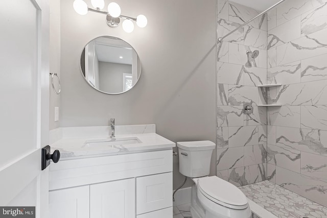 bathroom with a tile shower, vanity, and toilet