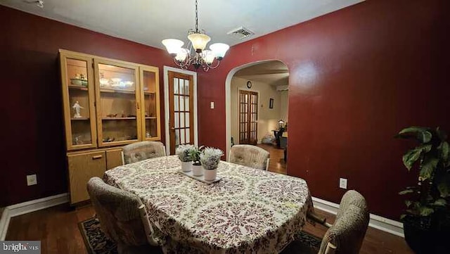 dining room featuring dark hardwood / wood-style flooring, french doors, and an inviting chandelier