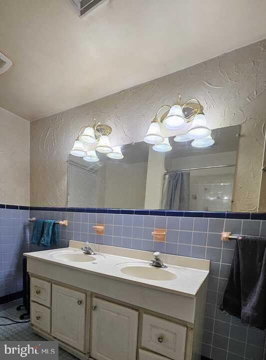 bathroom with vanity, tile walls, and walk in shower