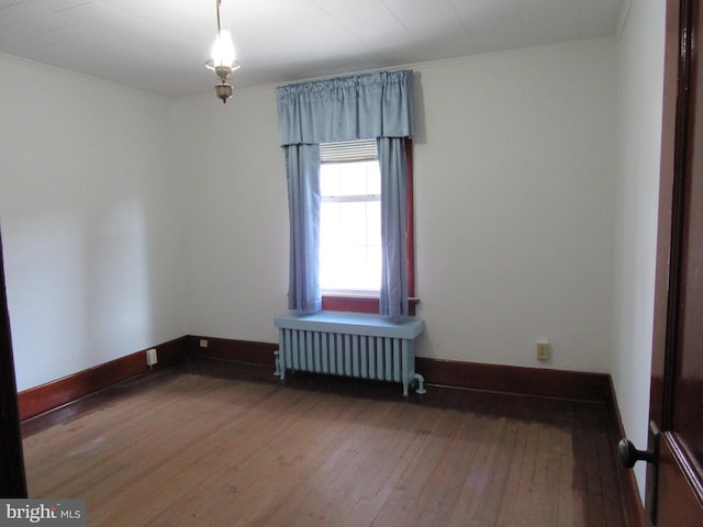 empty room featuring hardwood / wood-style floors, radiator heating unit, and crown molding