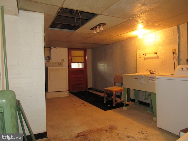 basement with a drop ceiling, independent washer and dryer, and sink