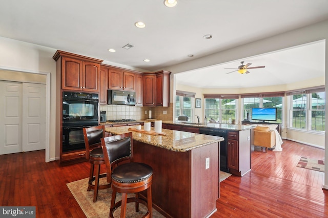 kitchen featuring ceiling fan, a center island, dark hardwood / wood-style floors, kitchen peninsula, and black appliances