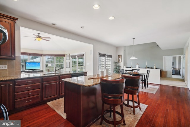 kitchen featuring a kitchen breakfast bar, light stone countertops, plenty of natural light, and a kitchen island