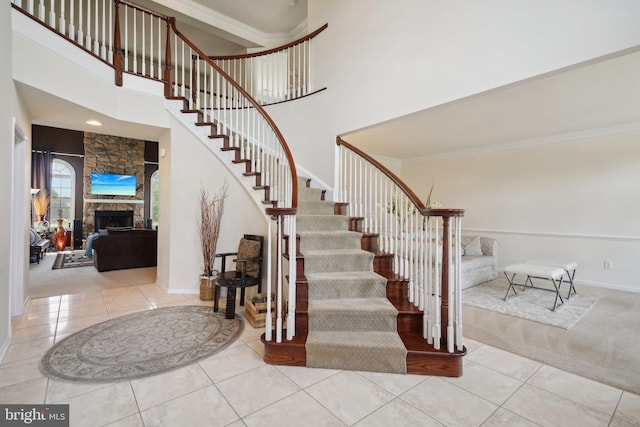 stairway featuring tile patterned flooring, a high ceiling, and a fireplace