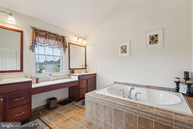 bathroom featuring tile patterned flooring, vanity, lofted ceiling, and tiled bath