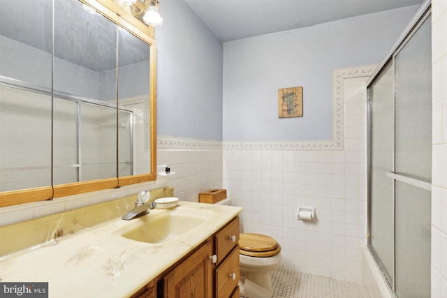 full bathroom featuring tile patterned floors, vanity, tile walls, enclosed tub / shower combo, and toilet