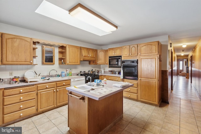 kitchen with light tile patterned floors, sink, an island with sink, and black appliances