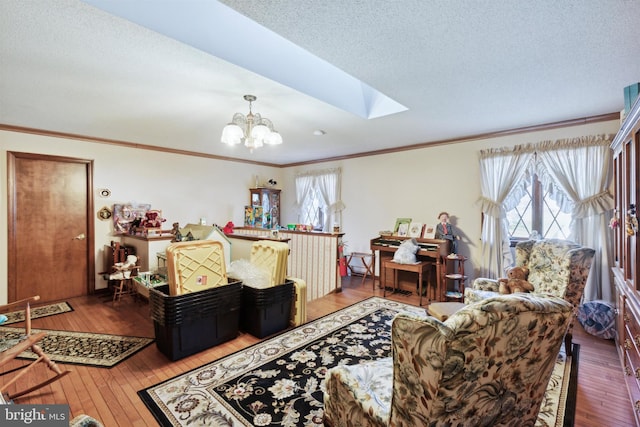 living room with a skylight, ornamental molding, wood-type flooring, and a notable chandelier