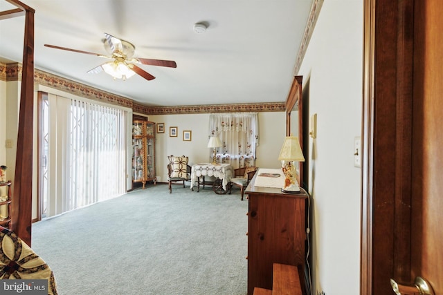 sitting room featuring carpet, ceiling fan, and crown molding