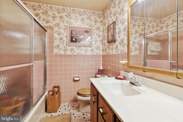 full bathroom featuring combined bath / shower with glass door, vanity, tile walls, tile patterned flooring, and toilet