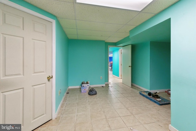 interior space with a paneled ceiling and light tile patterned flooring