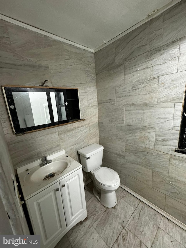 bathroom featuring vanity, toilet, and tile walls